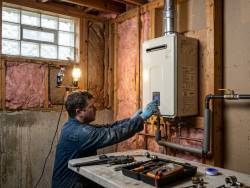 Wall-mounted gas tankless water heater being commissioned during install in a Knoxville home utility room